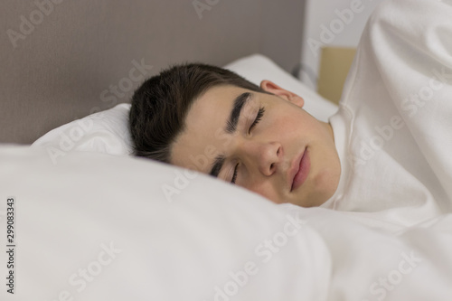 portrait of young teenage man sleeping in bed