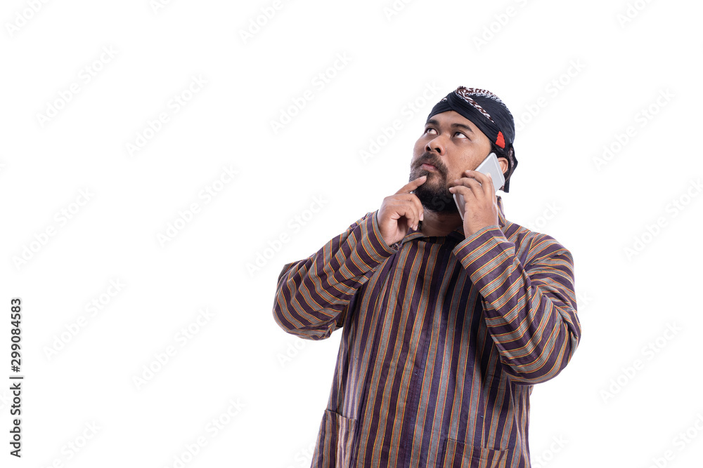 asian man with javanese traditional cloth lurik talking to his phone isolated over white background asian man with javanese traditional cloth lurik talking to his phone isolated over white background
