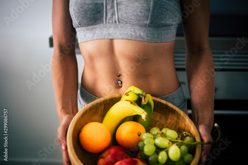 Close up of beautiful female muscle abdominal abs and mixed healthy fruit for fit lifestyle peope - diet and weight loss with vitamins and seasonal freuits photo