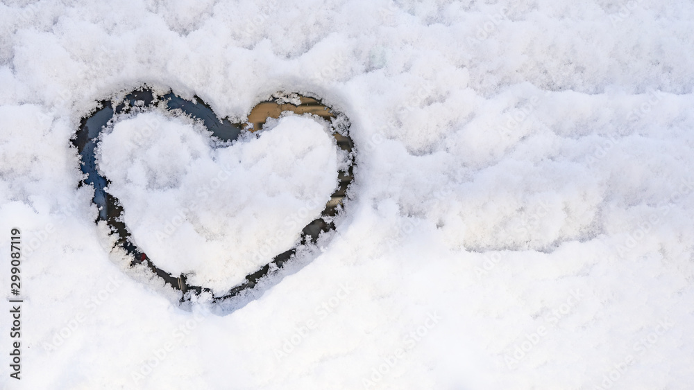 A heart drawn on a snowy glass. The concept of a winter, festive mood.