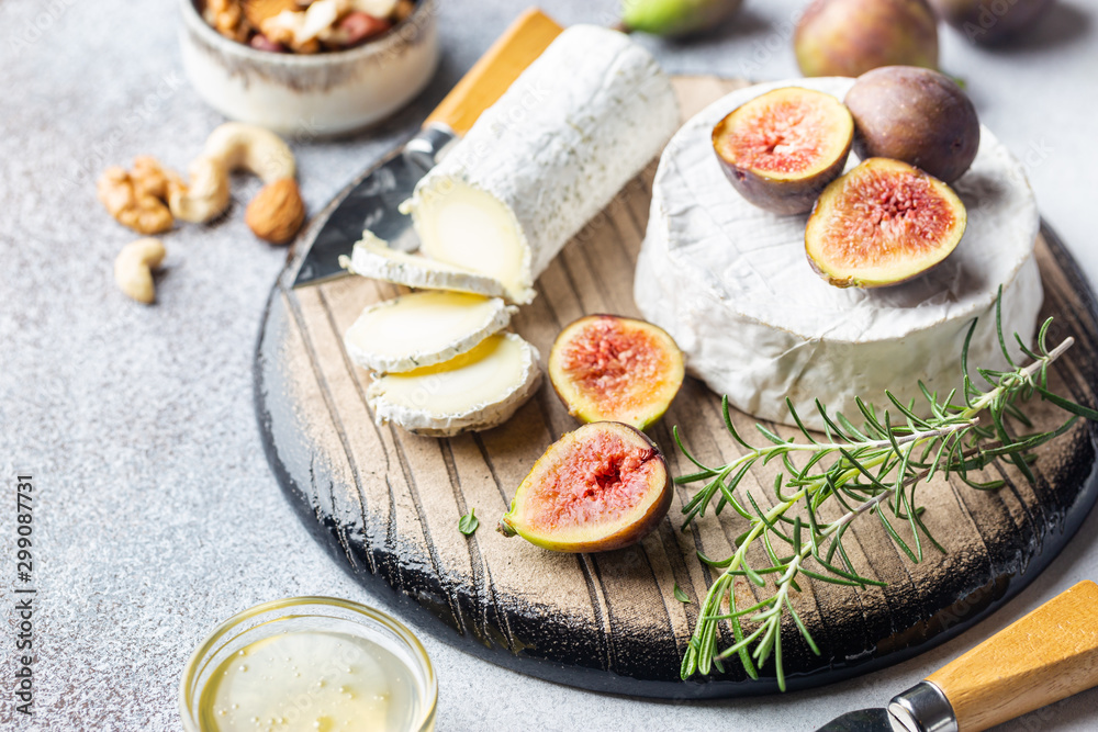 Fresh goat brie cheese with truffle and white mold on cheese platter with figs and honey Fresh goat brie cheese with truffle and white mold on cheese platter with figs and honey