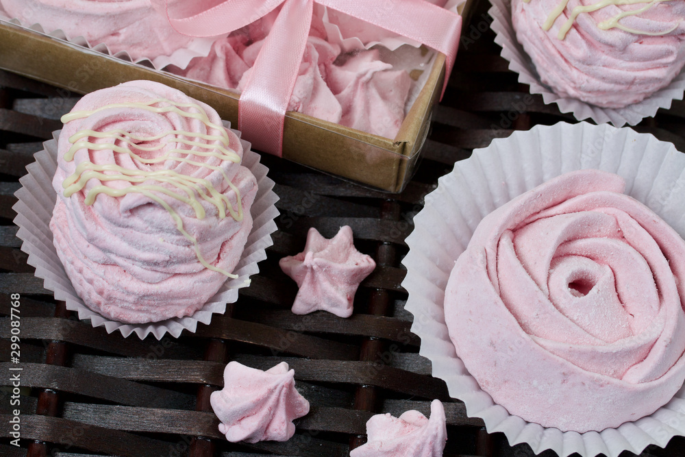 Aerial pink cherry marshmallows. In a gift box with a transparent cover. Near the marshmallows without packaging. Against the background of wicker vines. Aerial pink cherry marshmallows. In a gift box with a transparent cover. Near the marshmallows without packaging. Against the background of wicker vines.