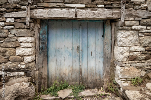 Brick wall with blue doors with weathered paint in Mikro Papingo in Zagori in Greece