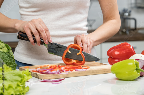 Close up of woman's hands cooking in the kitchen. Housewife slicing fresh Bell pepper. Vegetarian and healthily cooking concept