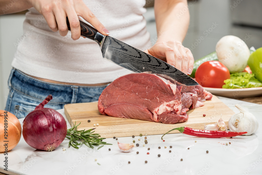 Close up of woman's hands cooking in the kitchen. Housewife slicing fresh meat.