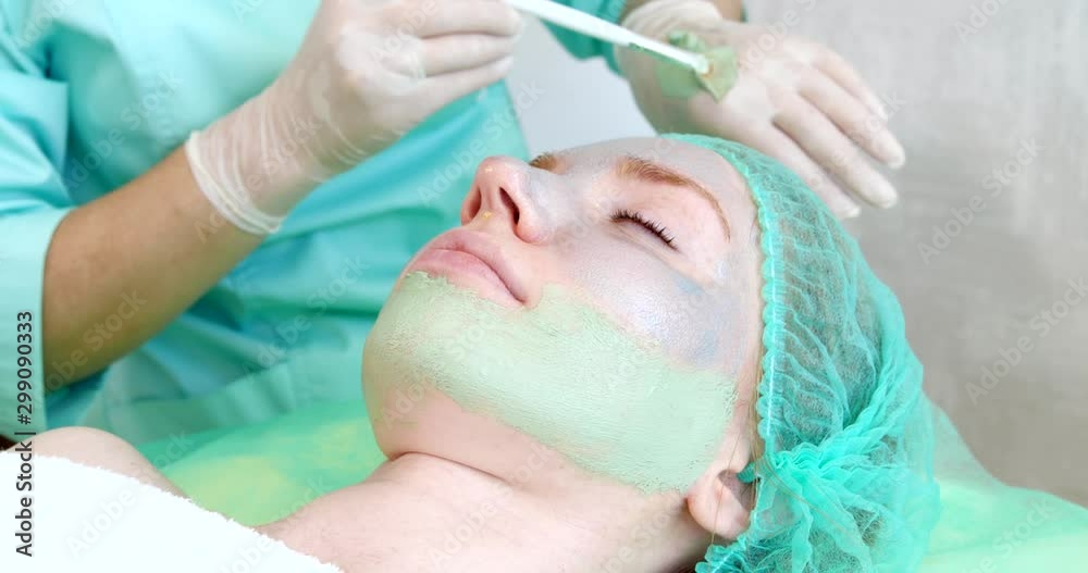 Cosmetologist applying mask onto woman's face in salon Cosmetologist applying mask onto woman's face in salon