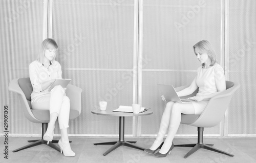 Black and white photo of businesswomen working while waiting in office lobby