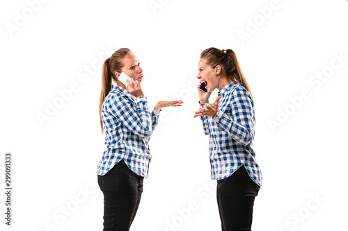 Young handsome woman arguing with herself on white studio background. Concept of human emotions, expression, mental issues, internal conflict, split personality. Half-length portrait. Negative space.