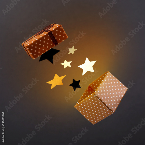Brown gift box with stars and yellow light on a dark background anti-gravity. © svitlini