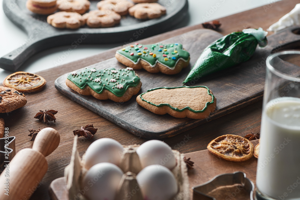 selective focus of baked Christmas cookies near ingredients on wooden table