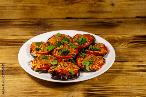 Baked eggplants with tomatoes and cheese on wooden table
