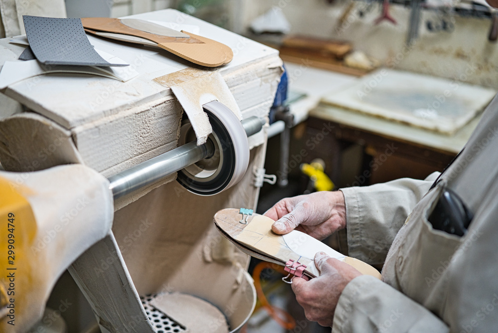 Obraz premium Professional craftsman of orthopedic insoles polishing, sanding and checking in his workshop the modeling of the templates with a fine sandpaper lathe. Hands covered in dust.
