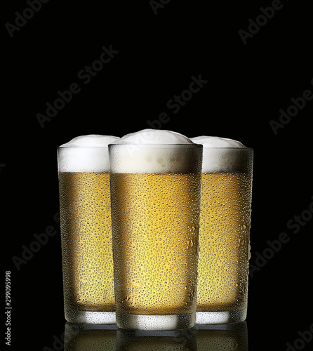Three cold Beer into glass on a dark background