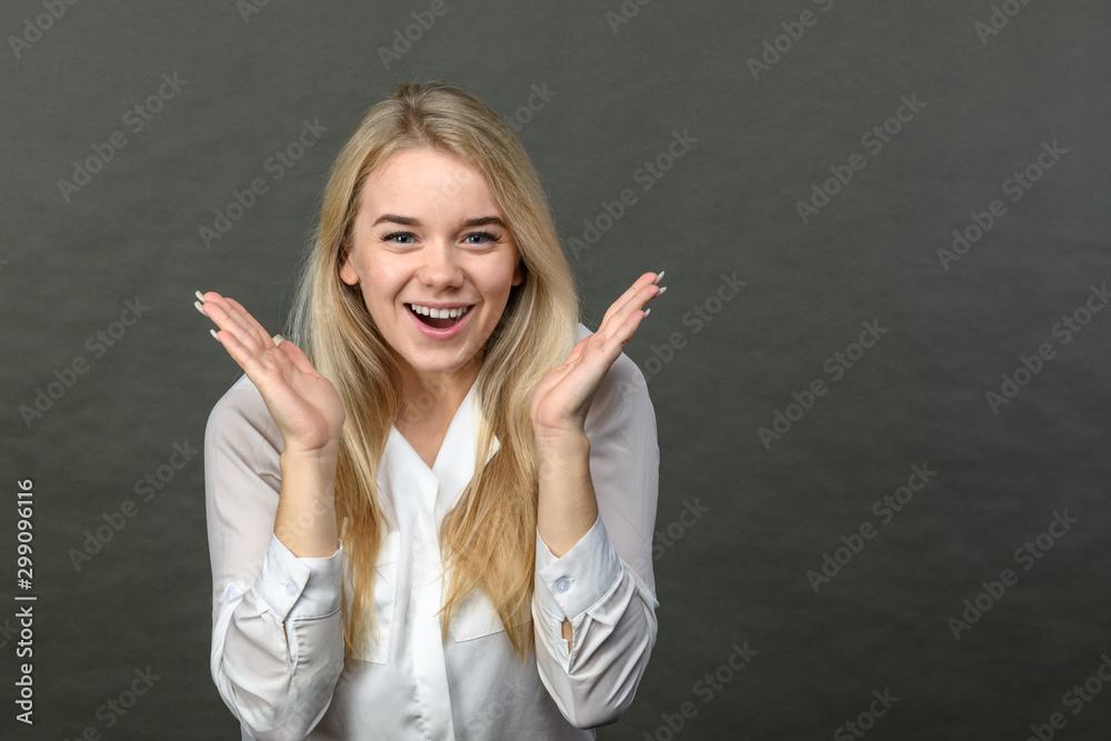 Portrait of young beautiful blonde woman smiling on grey background. Copy space.