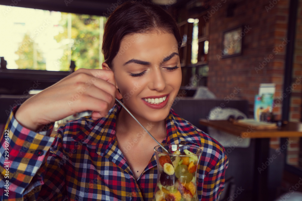 Attractive happy young woman sitting and eating dessert in cafe Attractive happy young woman sitting and eating dessert in cafe