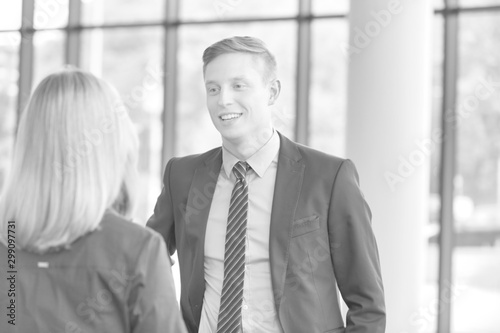 Black and white photo of Young businessman talking with businesswoman in office during meeting