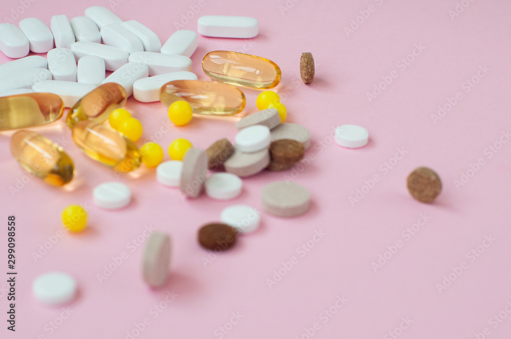 Assorted pharmaceutical medicine pills, tablets and capsules on pink background. Top view. Flat lay. Copy space. Medicine concept.