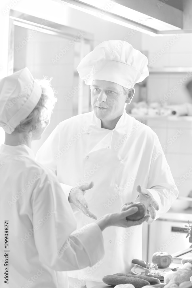 Black and white photo of Mature chefs discussing ingredients while standing at kitchen restaurant