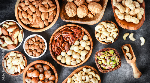 A variety of nuts in wooden bowls from top view. Walnuts, cashew, almond, pistachio, pecan, hazelnut, macadamia nut selection. Healthy super food.