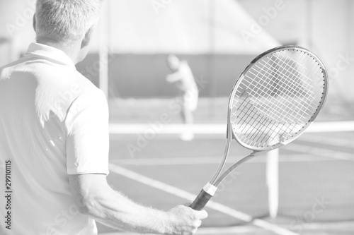 Active seniors playing tennis on sunny day at red court