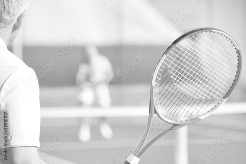 Active seniors playing tennis on sunny day at red court