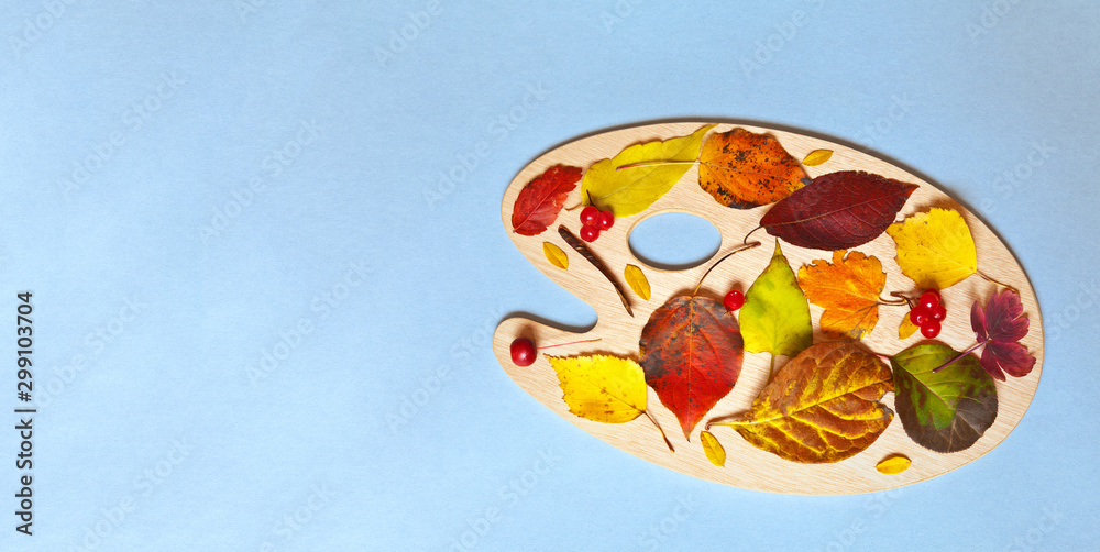 Autumn composition of beautiful multi-colored fallen leaves on an art palette on a light blue background. Space for text on the left. Flat lay, close-up, top view, copy space, layout, greeting card
