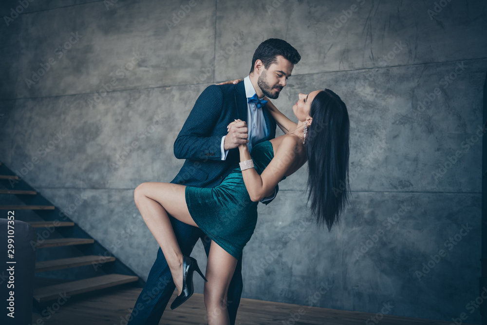 Profile photo of two stylish trendy people couple guy and lady slow dancing bending back holding hands bride and fiance tango wear luxury formalwear suit short mini dress loft indoors