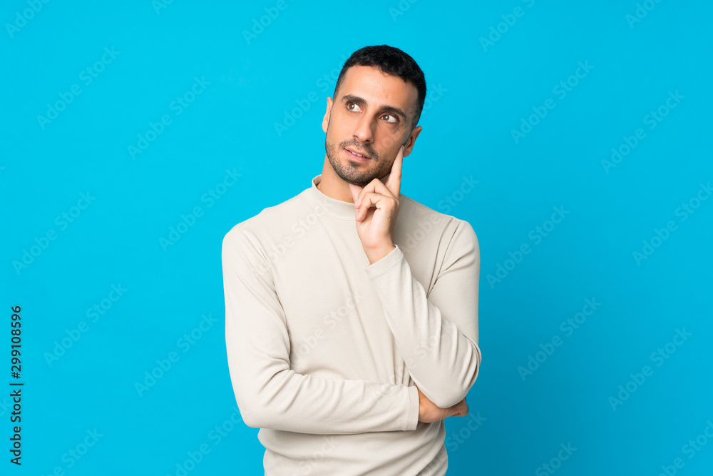 Young man over isolated blue background thinking an idea while looking up Young man over isolated blue background thinking an idea while looking up