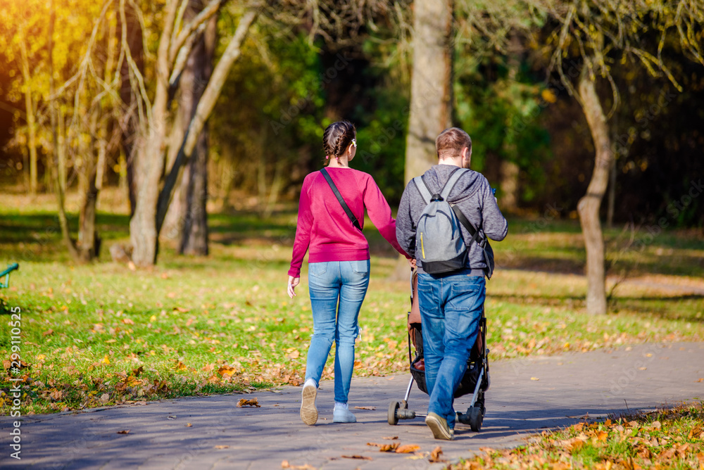 A married couple rolls a baby stroller in a city Park A married couple rolls a baby stroller in a city Park