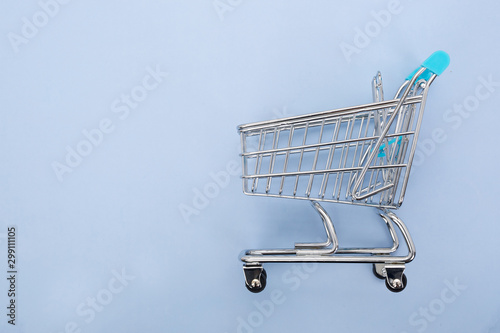 Miniature shopping cart isolated on blue background with copy space