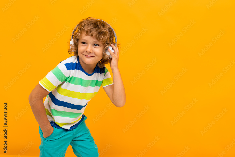 cheerful curly schoolboy on an orange background in headphones cheerful curly schoolboy on an orange background in headphones