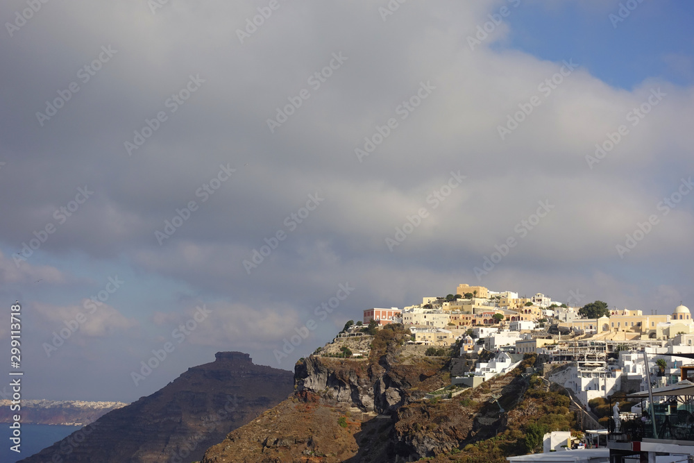 Picturesque and beautiful village of Fira overlooking the caldera with beautiful clouds and blue sky, Santorini island, Cyclades, Greece