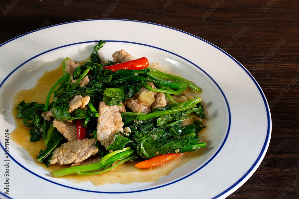 Stir fried kale with pork in white dish, Thai food Stir fried kale with pork in white dish, Thai food