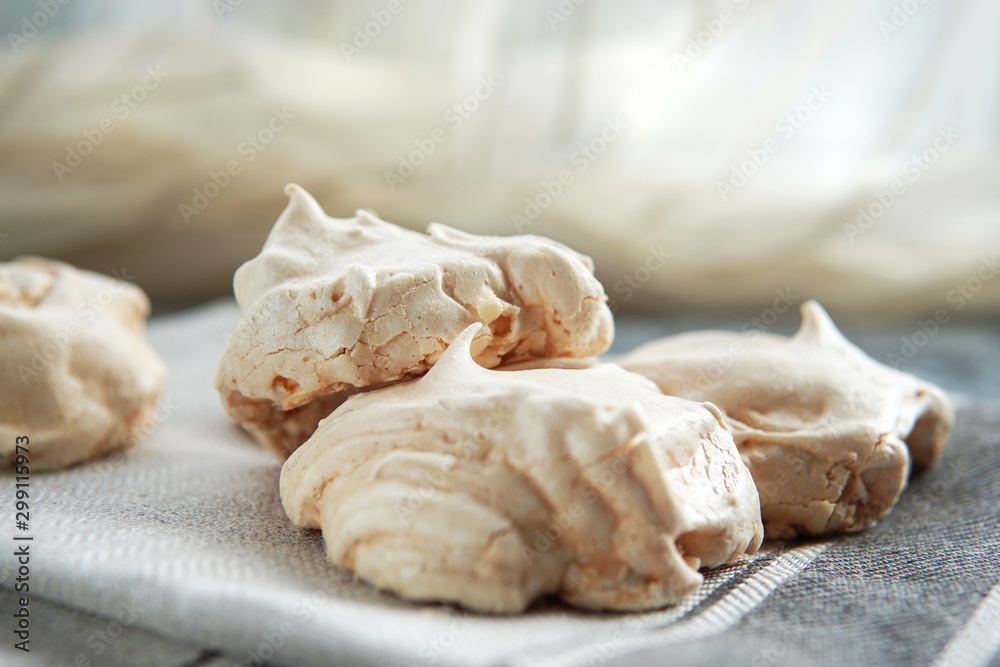 Homemade white meringue  cookies on linen textile. Selective focus.  Morning light. Beautiful dessert or breakfast. - obrazy, fototapety, plakaty 