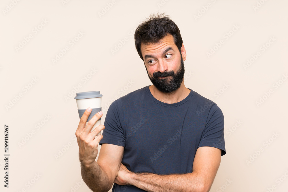 Man with beard holding a coffee with sad expression Man with beard holding a coffee with sad expression