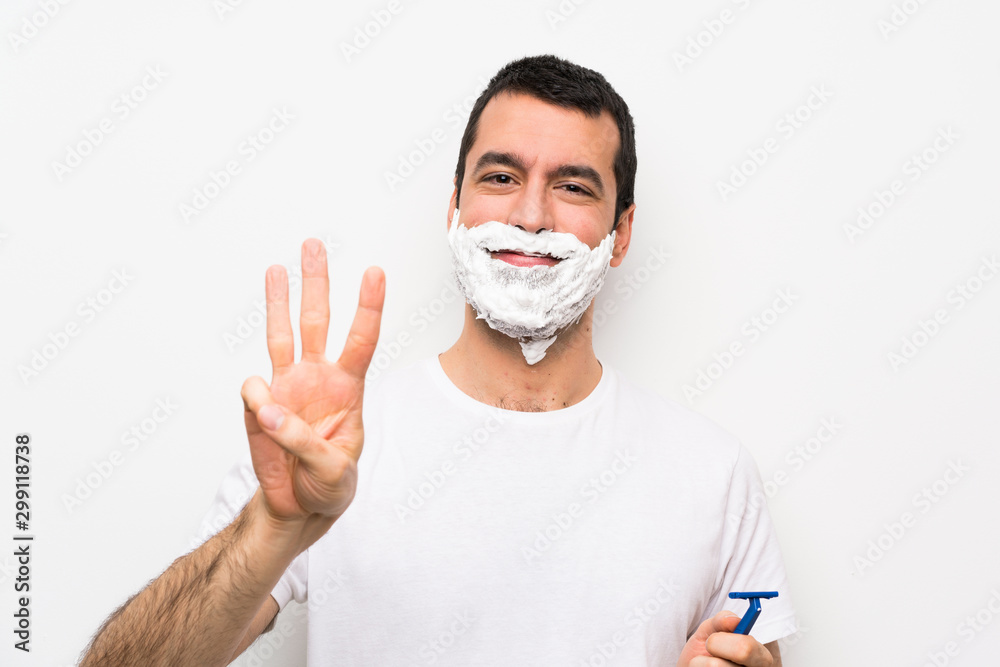 Man shaving his beard over isolated white background happy and counting three with fingers