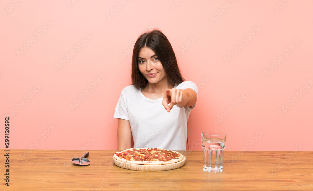 Young woman with a pizza points finger at you with a confident expression Young woman with a pizza points finger at you with a confident expression