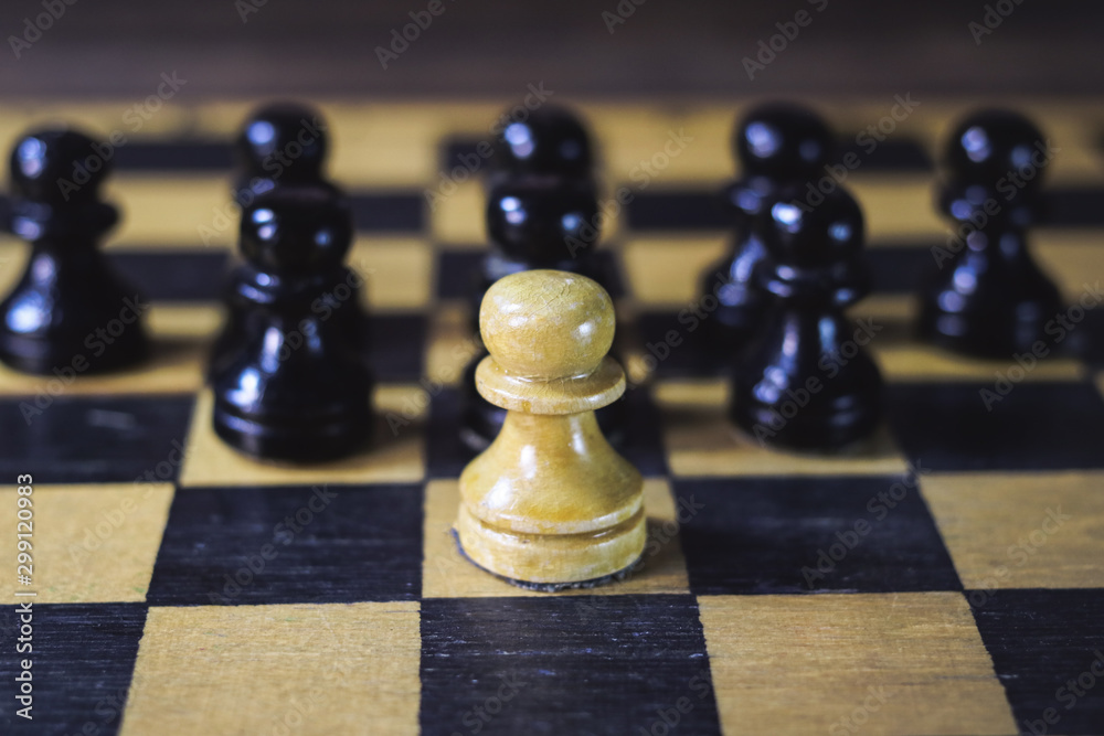 one white chess piece against a background of black pieces.
