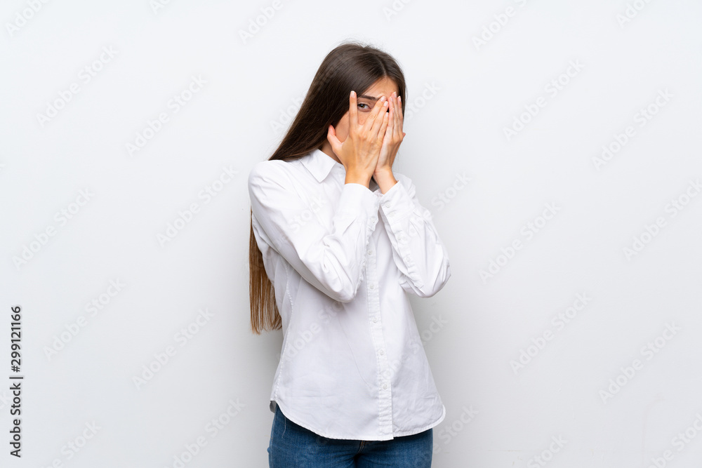 Young woman over isolated white background covering eyes and looking through fingers Young woman over isolated white background covering eyes and looking through fingers