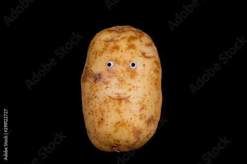 An isolated image of a potato with googly eyes and a face against a black background