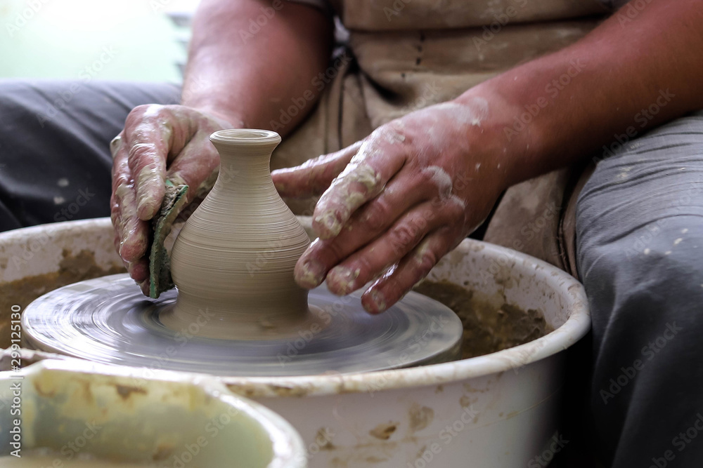 Male hands working on a potter wheel closeup. Making dishes from clay.