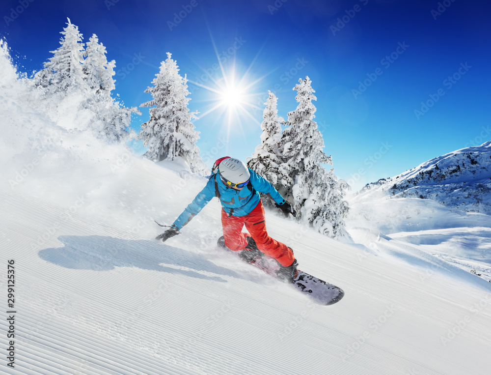 Young man snowboarder running down the slope in Alpine mountains