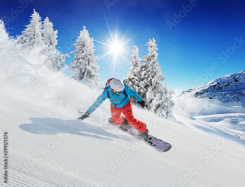 Young man snowboarder running down the slope in Alpine mountains