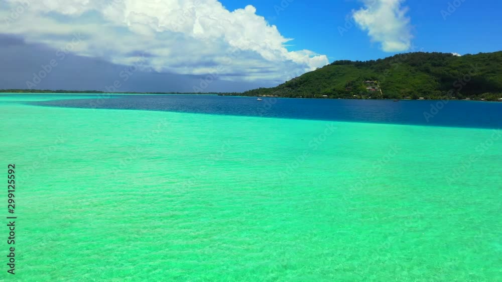 Aerial of a beautiful blue lagoon by a tropical island, drone flying forward over the water towards the island - Bora Bora, French Polynesia Aerial of a beautiful blue lagoon by a tropical island, drone flying forward over the water towards the island - Bora Bora, French Polynesia