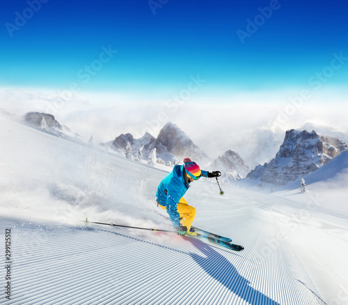 Young man skier running down the slope in Alpine mountains