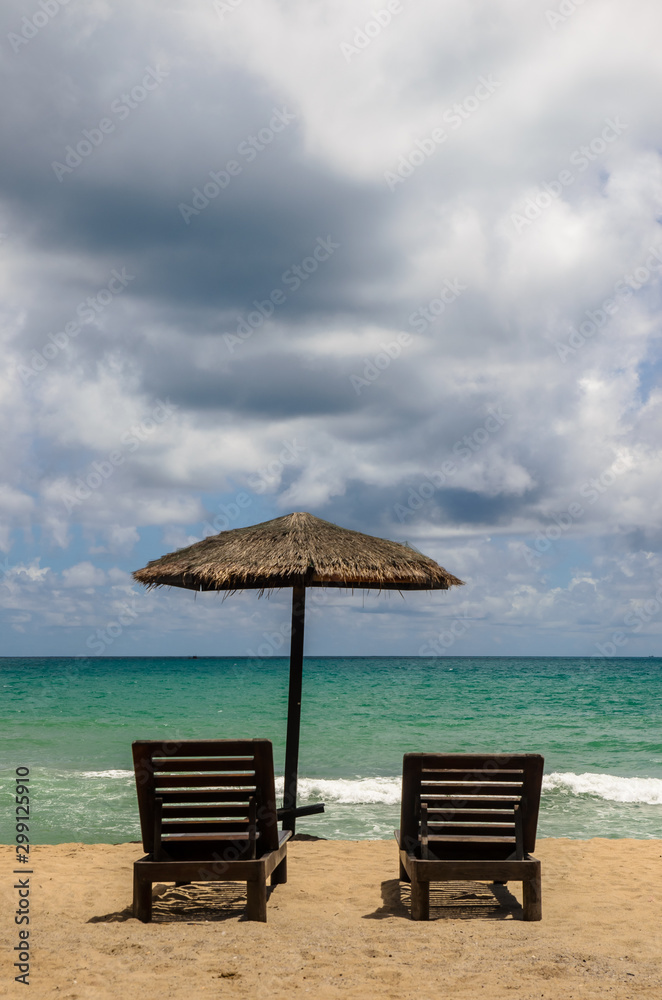 The beach chairs on sandy beach with cloudy blue sky and sun in the summer