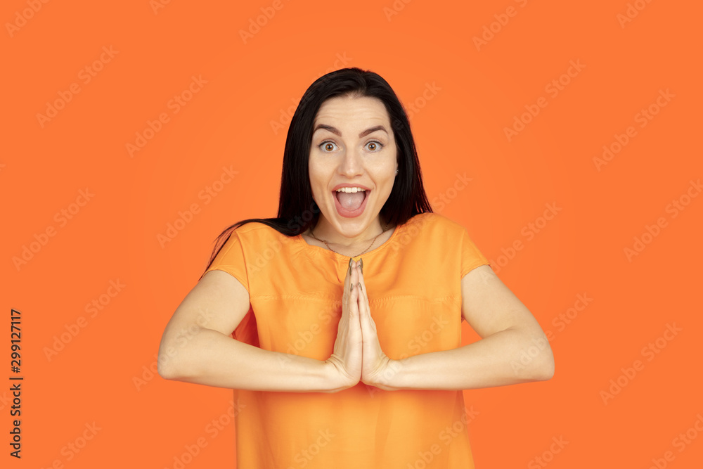Obraz premium Caucasian young woman's portrait on orange studio background. Beautiful female brunette model in shirt. Concept of human emotions, facial expression, sales, ad. Copyspace. Smiling, laughting.