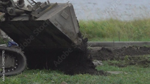 road construction: scraper-bulldozer (earth-mover) pours soil for highway building photo