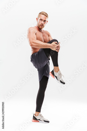 Handsome young concentrated sportsman doing stretching