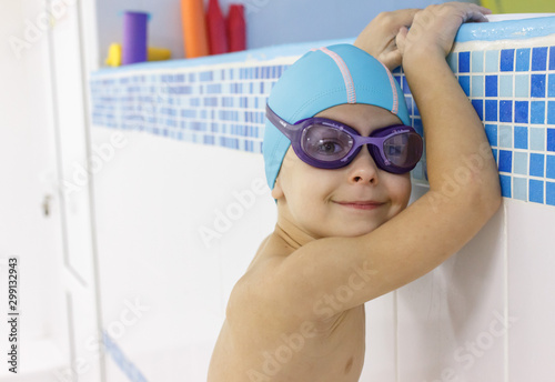 Happy boy in glasses and swimming cap in pool is ready to swim. Hardening. Workout. Sport. Space for text.